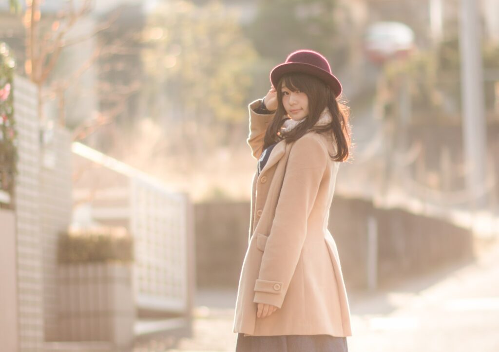 路地で後ろを振り返るコート姿の女性